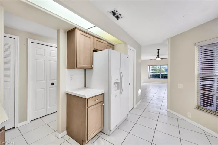 Kitchen with white refrigerator with ice dispenser, light tile patterned floors, and ceiling fan