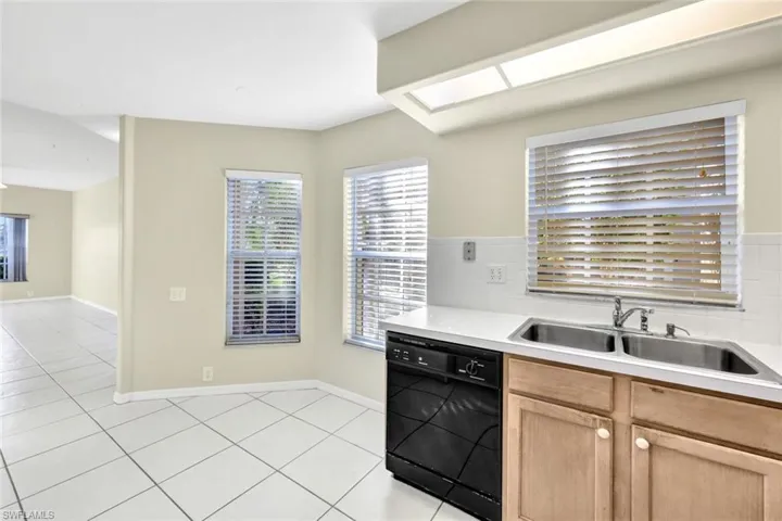 Kitchen with dishwasher, decorative backsplash, light tile patterned flooring, and sink
