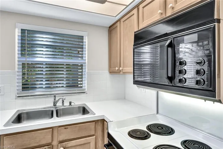 Kitchen featuring decorative backsplash, sink, and white range