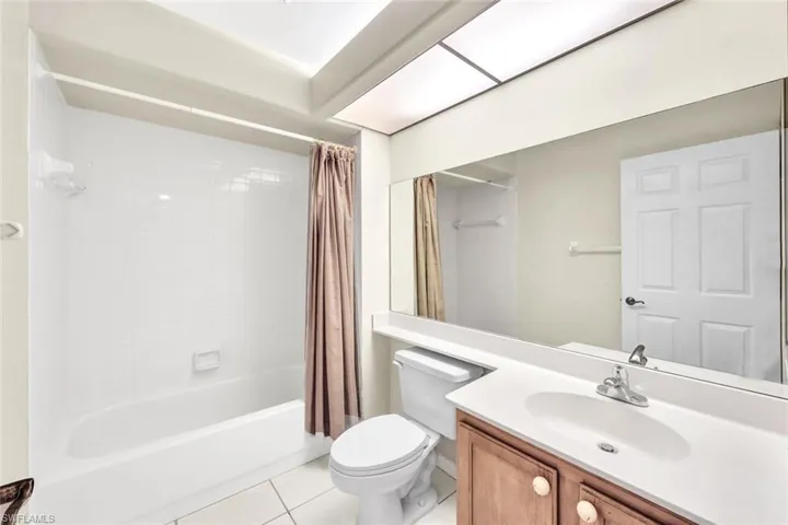 Full bathroom with tile patterned floors, vanity, shower / tub combo, and toilet