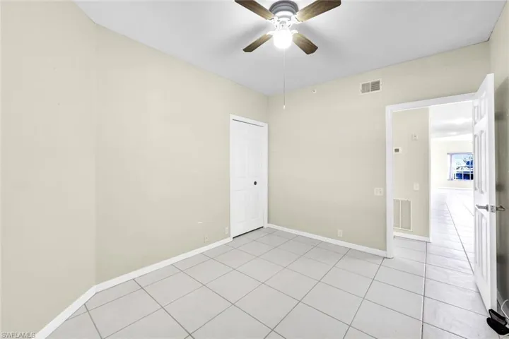 Tiled spare room featuring ceiling fan