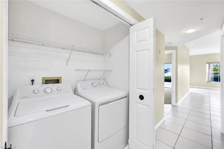 Washroom with washer and clothes dryer and light tile patterned flooring