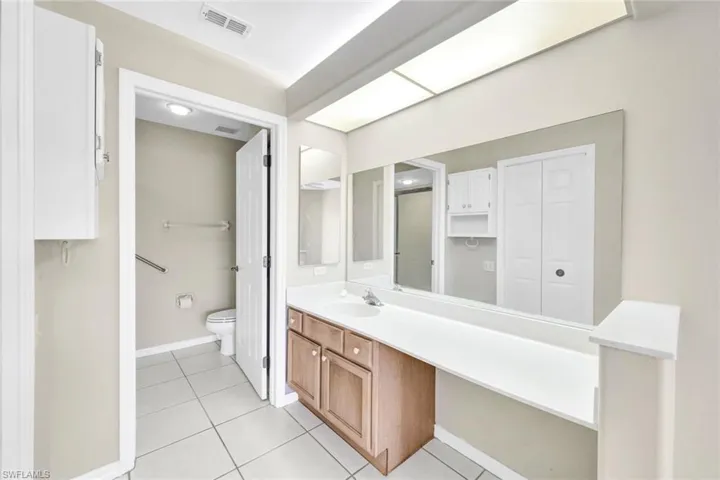 Bathroom with toilet, vanity, and tile patterned floors