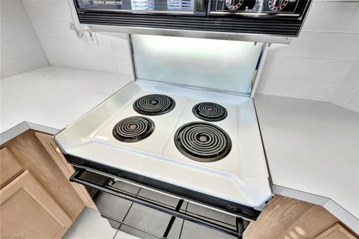 Room details with white range oven and light brown cabinetry