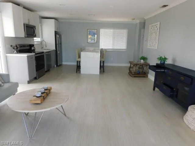 Living area featuring crown molding and light wood-type flooring