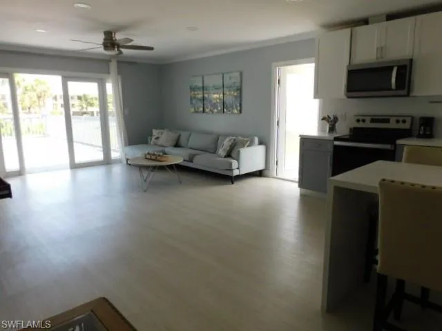 Living room featuring a ceiling fan, light wood-style floors, and crown molding