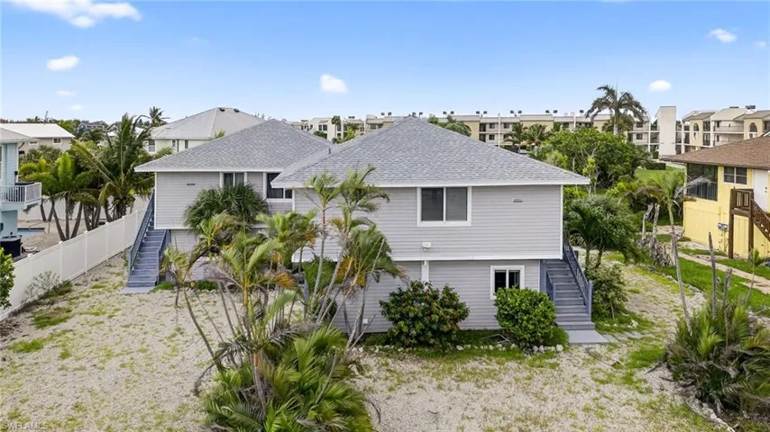 Back of property with stairway, roof with shingles, and a residential view