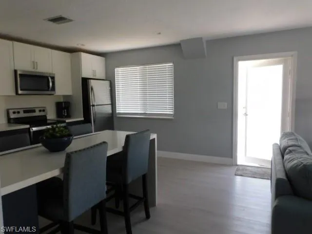 Kitchen featuring stainless steel appliances, light wood-style flooring, white cabinets, a breakfast bar area, and open floor plan