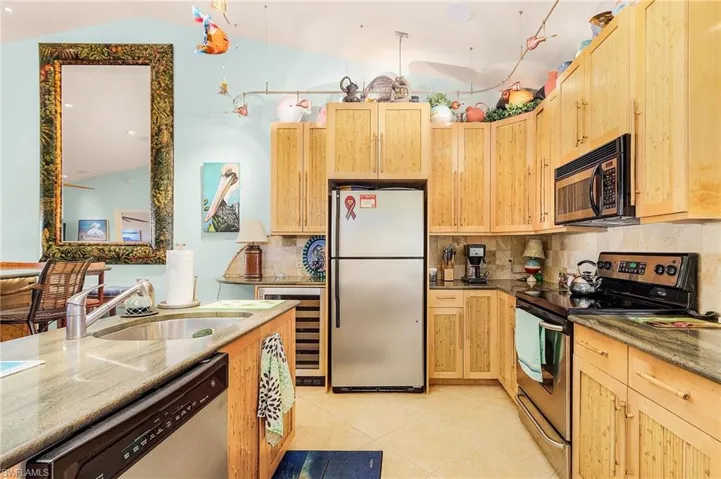 Kitchen featuring lofted ceiling, tasteful backsplash, light tile floors, and stainless steel appliances