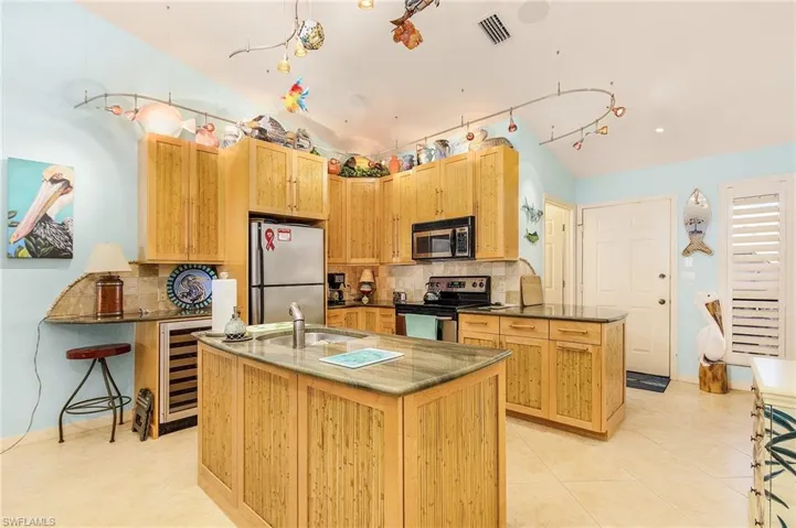Kitchen featuring an island with sink, sink, tasteful backsplash, and stainless steel appliances