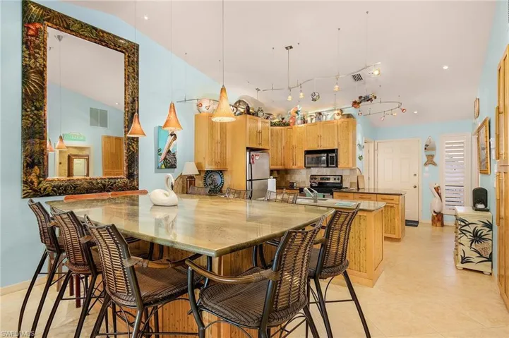 Kitchen with hanging light fixtures, appliances with stainless steel finishes, kitchen peninsula, backsplash, and light tile floors