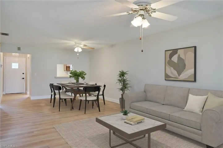 Living room with a ceiling fan, light wood-style flooring, and baseboards