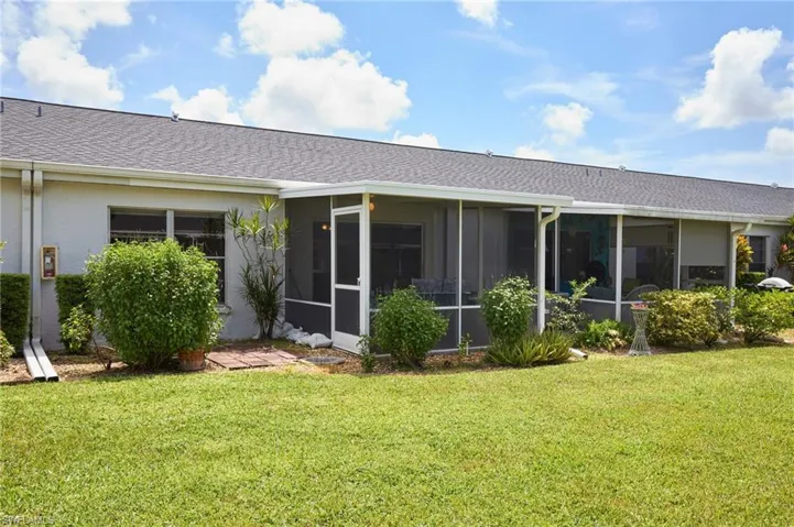 Rear view of property with a sunroom, a lawn, and a shingled roof