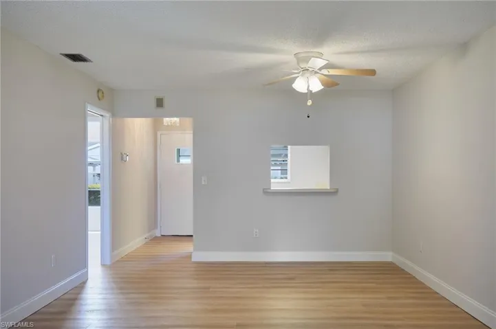 Unfurnished room featuring light wood-style flooring, ceiling fan, baseboards, and a textured ceiling