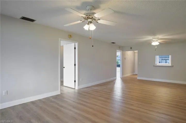 Unfurnished room featuring a ceiling fan, light wood-type flooring, baseboards, a textured ceiling, and a smoke detector