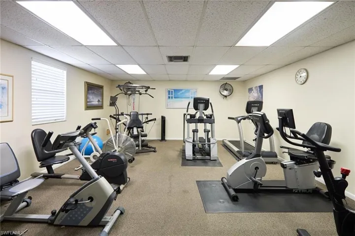 Gym with a drop ceiling and baseboards