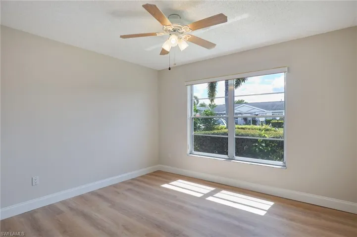 Unfurnished room featuring wood finished floors, baseboards, a textured ceiling, and a ceiling fan