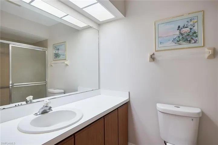 Bathroom featuring toilet, tiled shower, and vanity