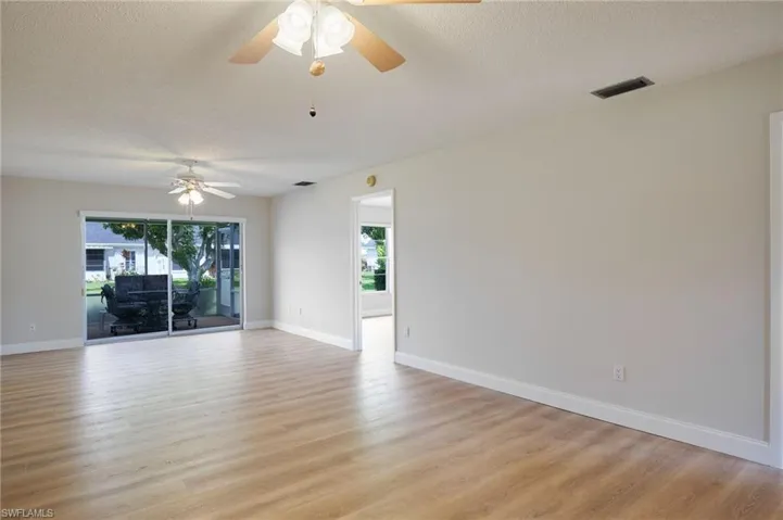 Spare room with ceiling fan, light wood finished floors, a textured ceiling, and baseboards