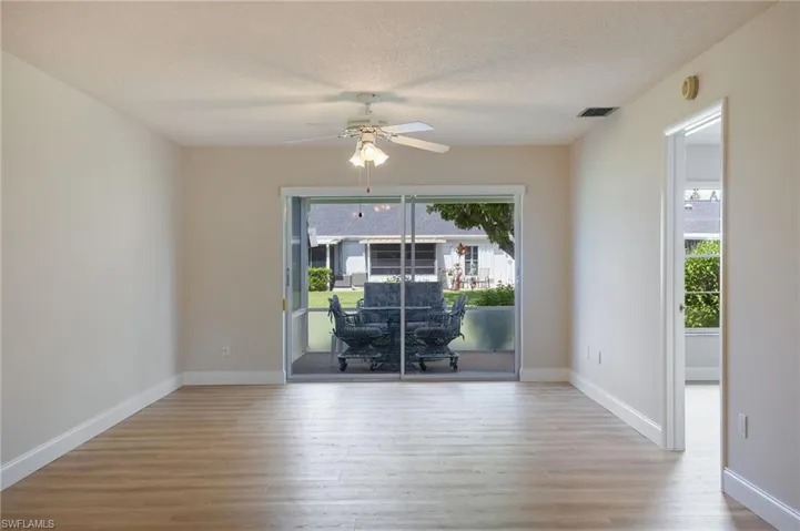 Empty room featuring wood finished floors, ceiling fan, plenty of natural light, a textured ceiling, and baseboards