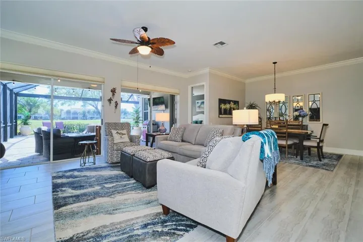 Living room with a sunroom, light wood-type flooring, ceiling fan, ornamental molding, and a chandelier