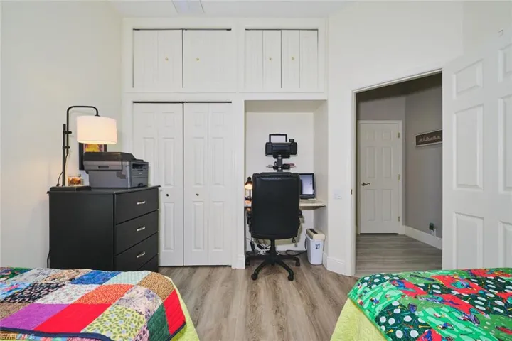 Bedroom with an office area, light wood-style flooring, and a closet