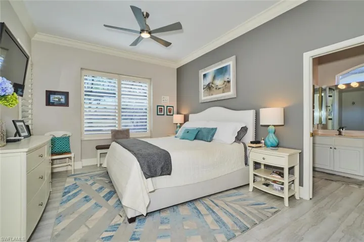 Bedroom with crown molding, ceiling fan, light wood finished floors, and connected bathroom