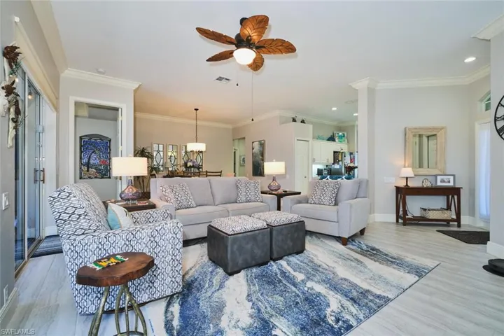 Living room with a ceiling fan, crown molding, and wood finished floors