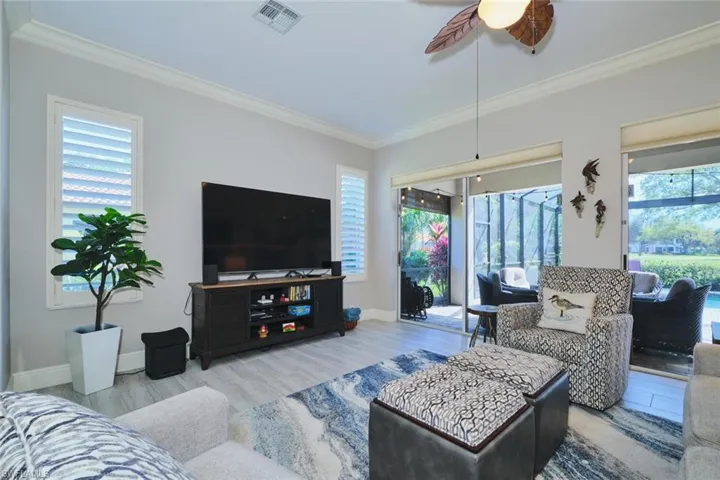 Living area with wood finished floors, plenty of natural light, ceiling fan, and crown molding