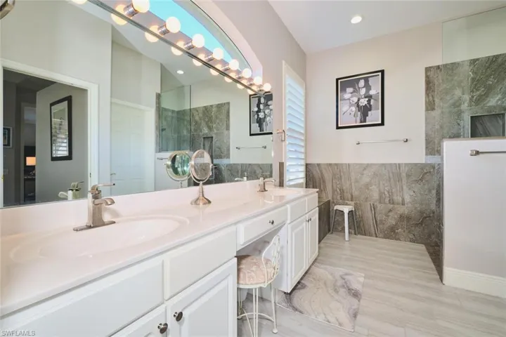 Bathroom with double vanity, tile walls, and walk in shower