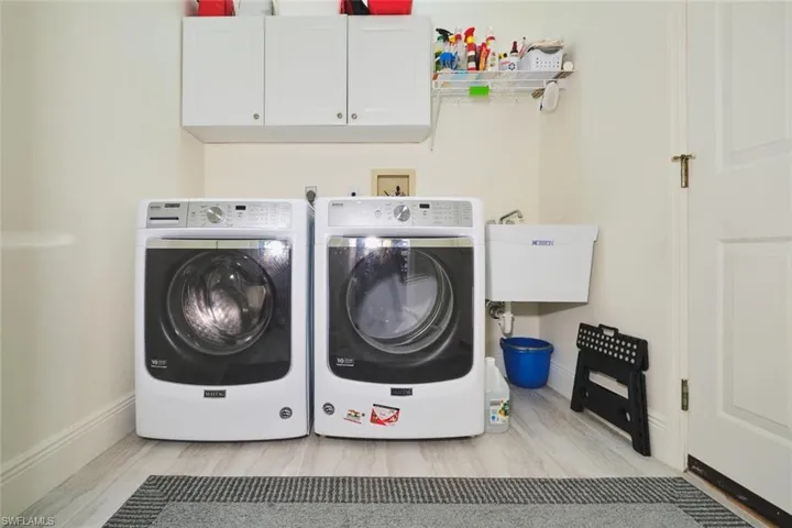 Laundry area featuring cabinet space, washing machine and clothes dryer, and light wood-style floors