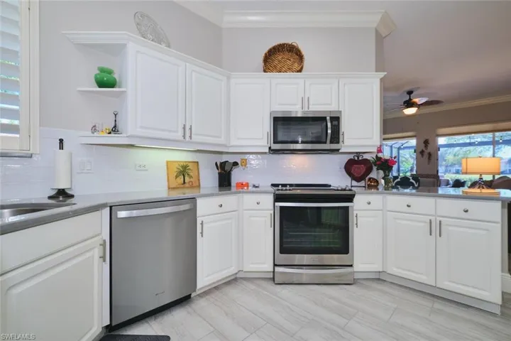 Kitchen with stainless steel appliances, white cabinets, ornamental molding, ceiling fan, and open shelves