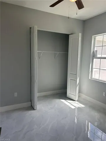 Unfurnished bedroom with ceiling fan and a closet