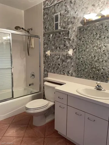 Bathroom with toilet, vanity, enclosed tub / shower combo, and tile patterned floors