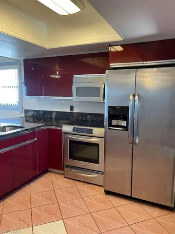 Kitchen featuring appliances with stainless steel finishes, a sink, and light tile patterned flooring