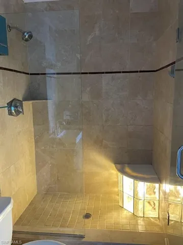 Full bath with tiled shower and toilet