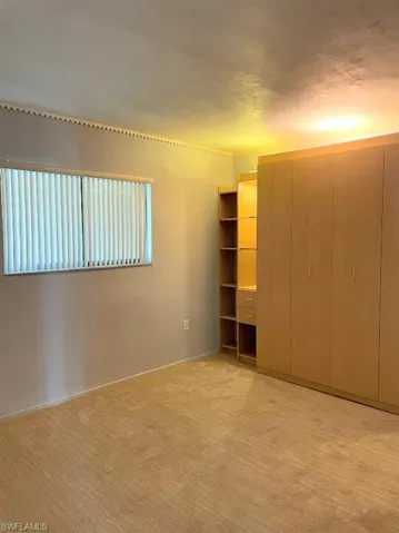 Unfurnished bedroom featuring light carpet, baseboards, and a closet