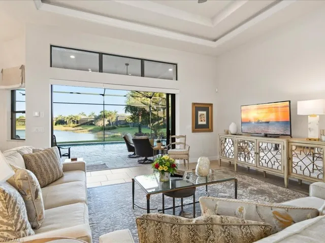 Living room with a raised ceiling, a water view, and a high ceiling