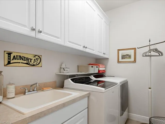 Clothes washing area with washer and dryer, cabinets, and sink