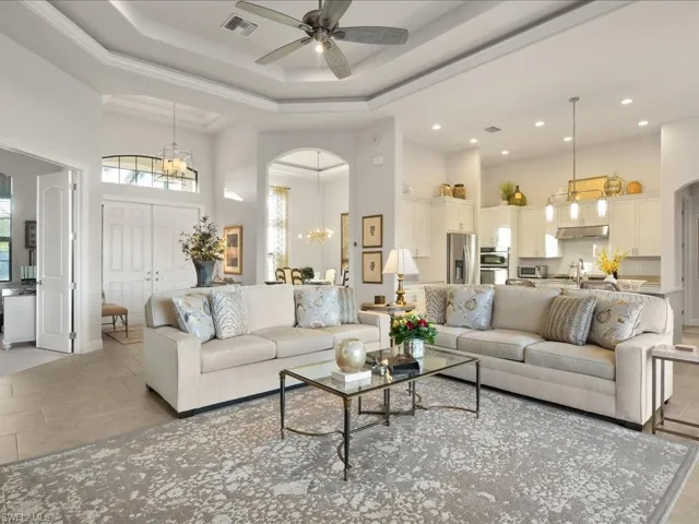 Living room with sink, a high ceiling, light tile patterned floors, ceiling fan with notable chandelier, and ornamental molding