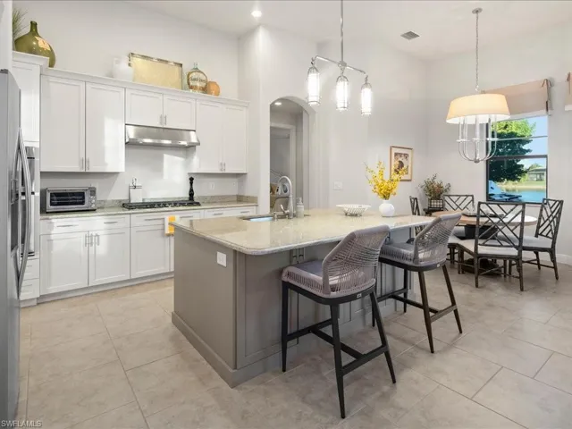 Kitchen with a kitchen bar, an island with sink, white cabinets, and pendant lighting