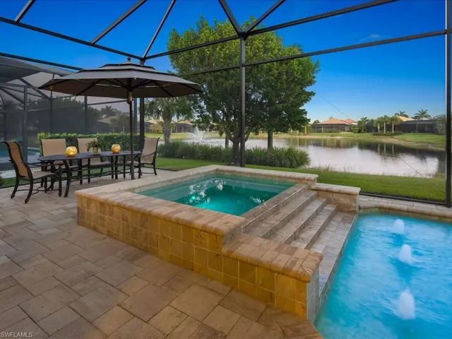 View of swimming pool featuring a lanai, a patio area, a water view, and an in ground hot tub