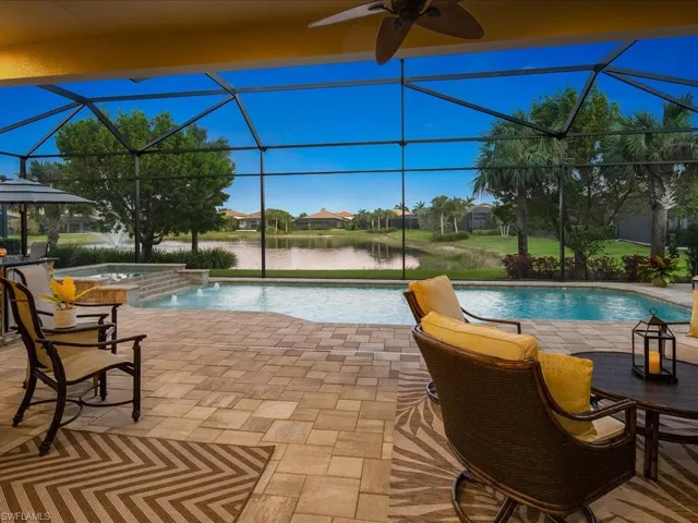View of pool with glass enclosure, an in ground hot tub, a water view, and pool water feature