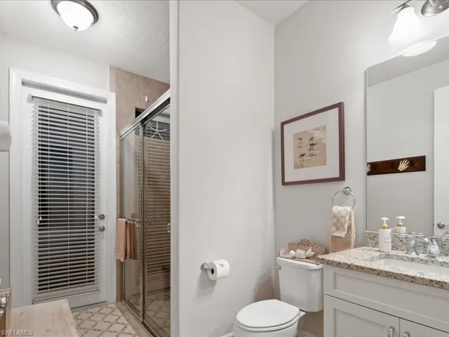 Bathroom with vanity, toilet, an enclosed shower, and a textured ceiling