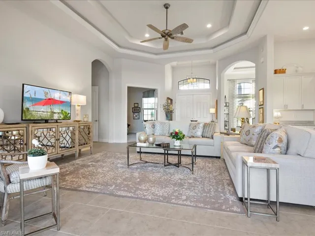Tiled living room with a tray ceiling, ceiling fan, and a towering ceiling