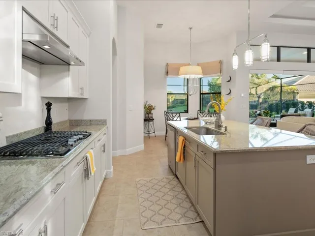 Kitchen with sink, stainless steel appliances, decorative light fixtures, a center island with sink, and white cabinets