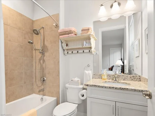 Full bathroom with vanity, tiled shower / bath, and toilet