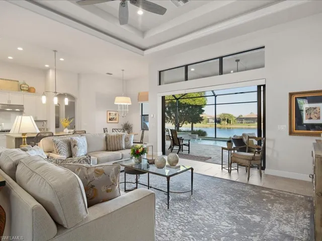Tiled living room with ceiling fan, a water view, and a high ceiling