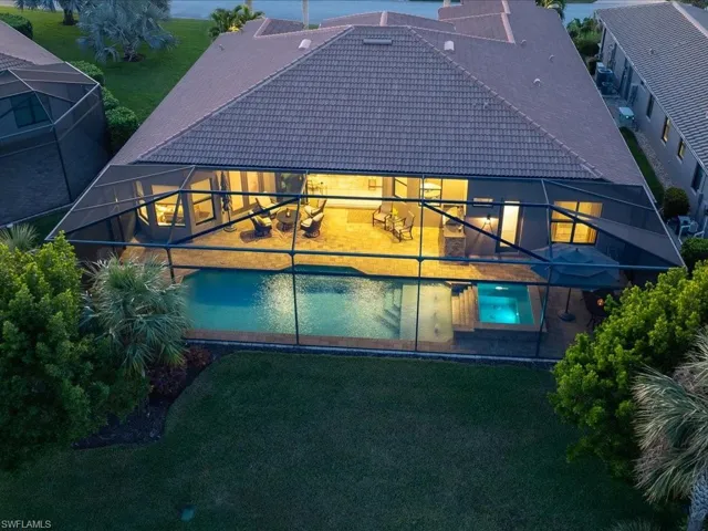 Rear view of property featuring a lawn, glass enclosure, and a patio area