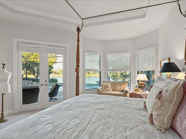 Bedroom with french doors, a raised ceiling, a water view, access to exterior, and carpet floors